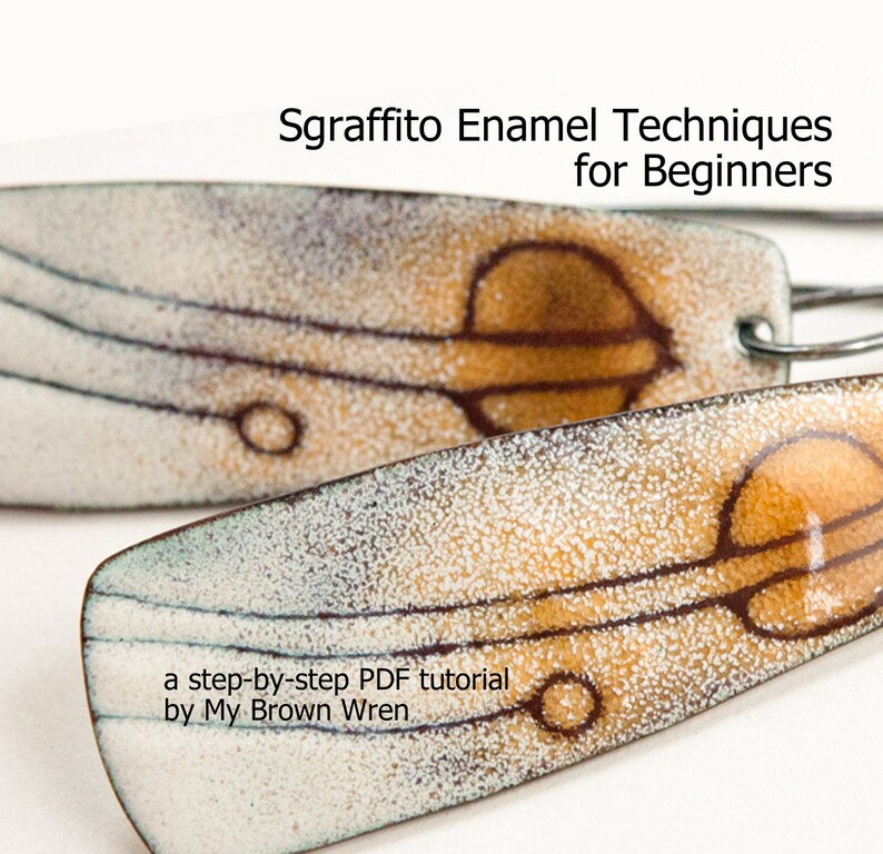 May include: A pair of earrings with a white and brown enamel design. The earrings feature a sgraffito technique, which is a decorative technique that involves scratching through a layer of enamel to reveal the underlying layer. The earrings are titled "Sgraffito Enamel Techniques for Beginners" and include a step-by-step PDF tutorial by My Brown Wren.