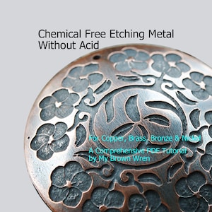Könnte beinhalten: Nahaufnahme einer runden Kupferscheibe mit einem geätzten Blumenmuster. Die Scheibe hat oben ein Loch und ist von einem grauen Hintergrund umgeben. Der Text "Chemical Free Etching Metal Without Acid" befindet sich oben im Bild. Der Text "For Copper, Brass, Bronze & Nickel" befindet sich unten im Bild. Der Text "A Comprehensive PDF Tutorial by My Brown Wren" befindet sich unter dem vorherigen Text.