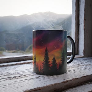 May include: A black coffee mug with a colorful sunset and silhouette of trees design. Steam rises from the mug.
