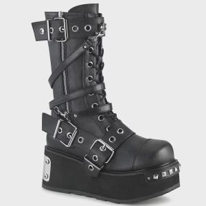 May include: Black platform boot with multiple straps, buckles, and a zip. The boot features silver metal accents, including studs on the platform sole. The boot has a lace-up design and a high shaft.