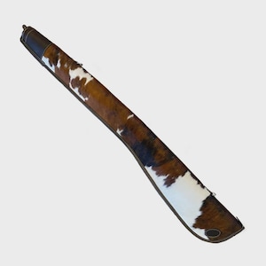 Puede incluir: Un estuche largo y delgado con un patrón de piel de vaca en tonos marrones y blancos. El estuche tiene un ribete y tapas de cuero marrón oscuro. El estuche está diseñado para guardar un objeto largo y delgado.