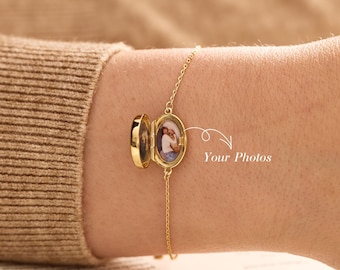 May include: A gold-toned metal locket bracelet featuring a delicate chain and an oval-shaped locket that opens to reveal two small photo inserts. The locket is positioned on a wrist, with white text overlay reading Your Photos.