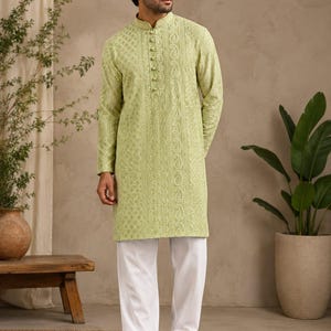 May include: A light green long-sleeved kurta featuring intricate tonal embroidery and a vertical row of decorative buttons along the mandarin collar, paired with plain white trousers and brown leather sandals, creating a traditional ensemble.