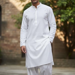 May include: A white, long-sleeved tunic and matching pants. The tunic has a mandarin collar and a buttoned placket. The pants are loose-fitting. The outfit is made of a lightweight fabric, suitable for warm weather.
