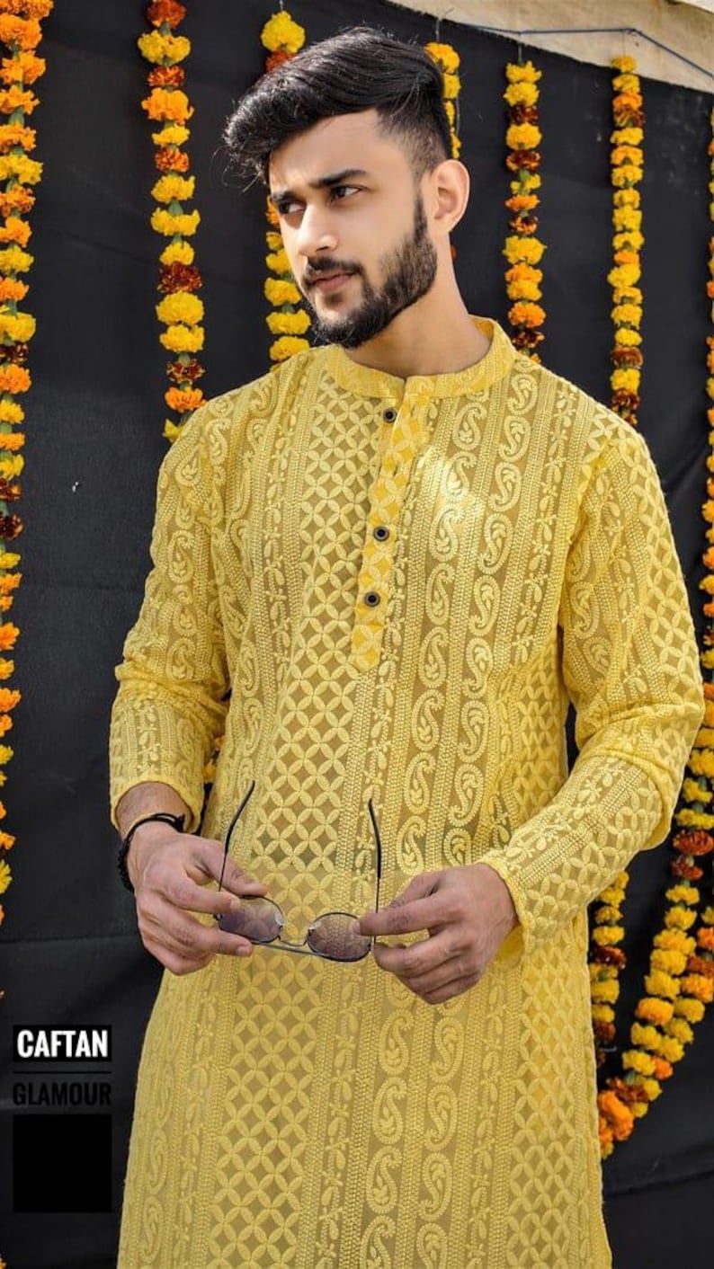 May include: A yellow long-sleeved shirt with a button-up collar and intricate embroidery. The shirt has a paisley pattern and a geometric design.