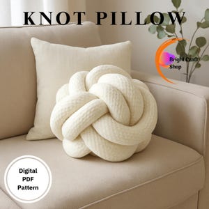 Puede incluir: Un cojín anudado de color crema descansa sobre un sofá beige, con un cojín cuadrado a juego detrás. Las palabras "KNOT PILLOW" están en la parte superior de la imagen. También hay un patrón PDF digital disponible.