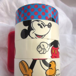May include: A multi-layered stacking cup featuring Mickey Mouse in a walking pose. The cup is decorated with blue and white polka dots, red and yellow polka dots, and a red handle.