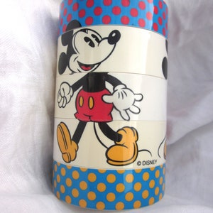 May include: A vintage stacking toy featuring Mickey Mouse. The toy is made of plastic and has a white background with a red, blue, and yellow polka dot pattern. The toy is labeled with the copyright symbol and the word "DISNEY".