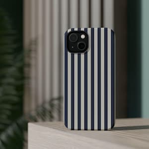 Op de afbeelding: Een smartphonehoesje met een verticaal gestreept patroon in marineblauw en lichtbeige. De hoes heeft een camera-uitsparing en wordt getoond op een lichtgekleurd oppervlak.