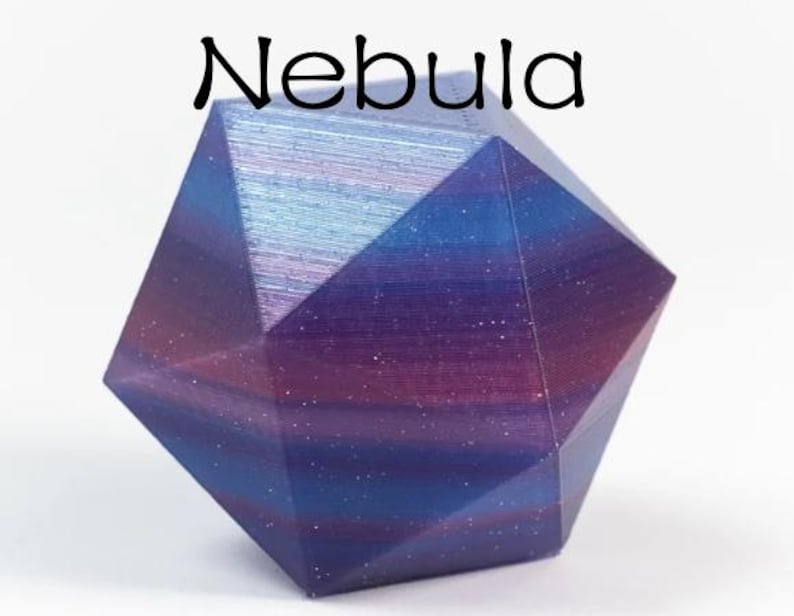May include: A multi-faceted geometric polyhedral object with a gradient colour finish transitioning between deep purple, magenta, and blue hues. The surface features a subtle glittery texture and the word Nebula is printed above it.
