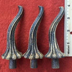 Op de afbeelding: Drie decoratieve toppen met een zwarte en gouden afwerking. De toppen zijn gevormd als een gebogen stengel met een afgeronde bovenkant. Ze zijn ongeveer 15 cm hoog.