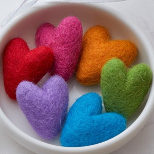 Könnte beinhalten: Sechs Filz-Herzen in verschiedenen Farben, darunter Rot, Pink, Orange, Grün, Lila und Blau. Die Herzen sind in einer Schüssel angeordnet.