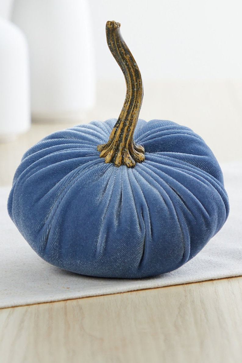 May include: A blue velvet pumpkin with a gold stem. The pumpkin is a decorative item for fall and autumn.