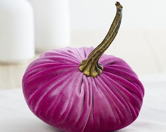 May include: A plush velvet pumpkin in a deep pink hue with a gold-toned stem. The pumpkin is a decorative accent for fall and Halloween.