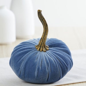 May include: A blue velvet pumpkin with a gold stem. The pumpkin is a decorative item for fall.