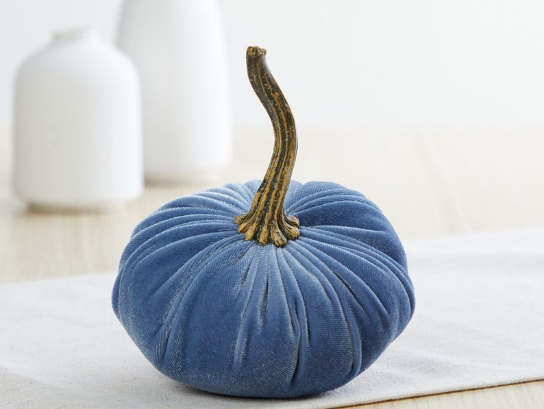 May include: A blue velvet pumpkin with a gold stem. The pumpkin is a decorative item for fall.