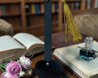 This is a handcrafted black pebbled leather bookmark with a tassel.