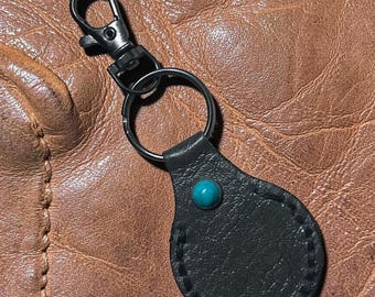 This is a handmade black leather key fob with a turquoise stone accent and a gunmetal clasp.