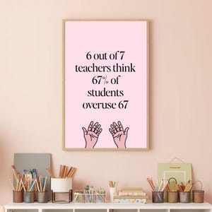 May include: A framed pink print with the text "6 out of 7 teachers think 67% of students overuse 67." The print also features two hands with open palms. The print is in a light brown frame.
