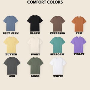May include: A collection of short-sleeved t-shirts in various colors, including blue jean, black, espresso, yam, butter, ivory, seafoam, violet, ash, moss, and white. The text "COMFORT COLORS" is at the top, with each shirt's color labeled below.