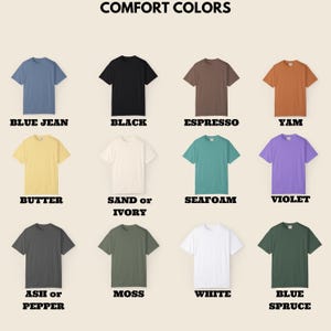 May include: A display of twelve short-sleeved t-shirts in various colors, including blue jean, black, espresso, and yam. The text "COMFORT COLORS" is at the top, with color names below each shirt. Other colors include butter, sand or ivory, seafoam, violet, ash or pepper, moss, white, and blue spruce.