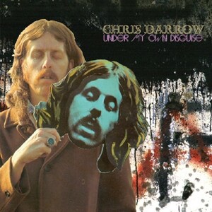 Puede incluir: Portada del álbum "Chris Darrow - Under My Own Disguise". La imagen muestra a un hombre sosteniendo una máscara de su propia cara. El fondo es oscuro con salpicaduras de pintura. El título del álbum y el nombre del artista son de color rosa.