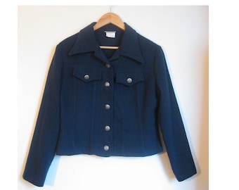 May include: A dark blue cropped jacket with a collar and button closure. The jacket has two flap pockets on the front and silver buttons.