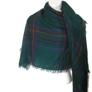 May include: A green plaid scarf with red, yellow and blue stripes. The scarf has a fringed edge.