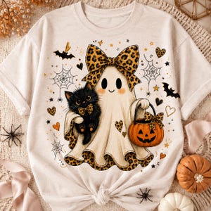 A white t-shirt with a Halloween-themed design featuring a ghost, a cat, a pumpkin, and various other Halloween-related elements.