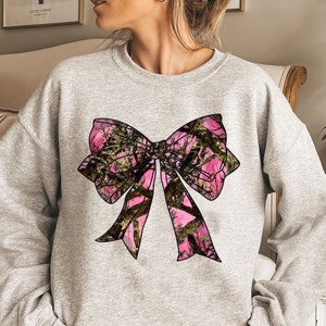a woman wearing a sweatshirt with a pink bow on it