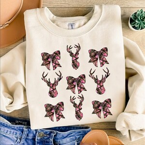 a white shirt with pink bows and deer heads on it