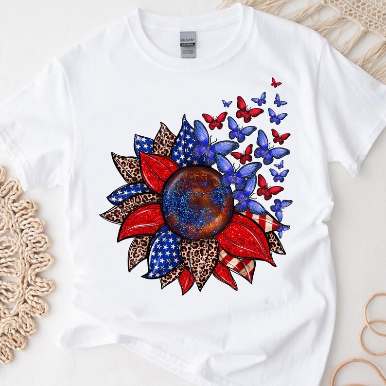 A white t-shirt with a vibrant graphic design depicting a sunflower surrounded by butterflies in red, blue, and white colors.