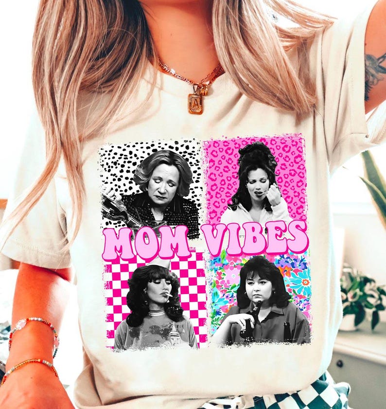 a woman wearing a white t-shirt with a graphic design that includes four different portraits of a woman, along with the text "MOM VIBES" prominently displayed.