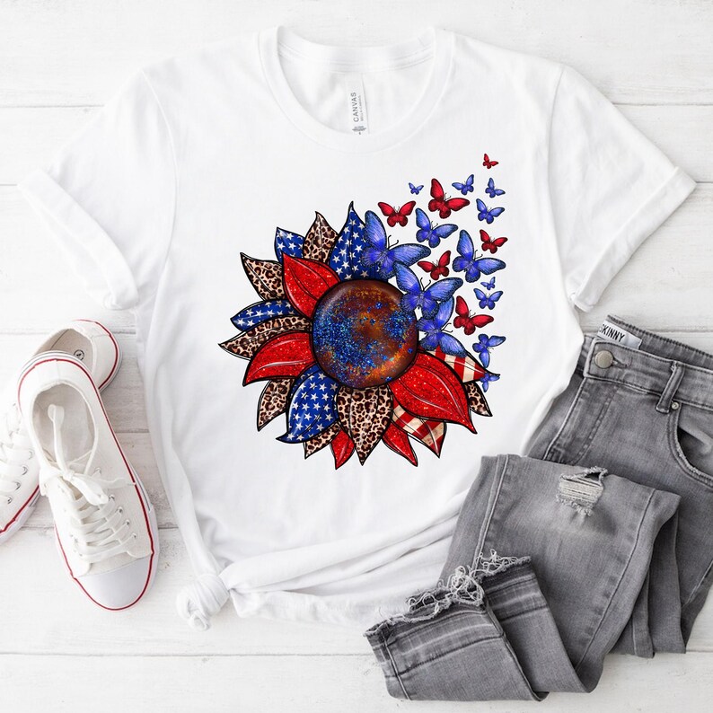 A white t-shirt with a colorful sunflower design and butterflies printed on it, along with a pair of jeans and white sneakers.