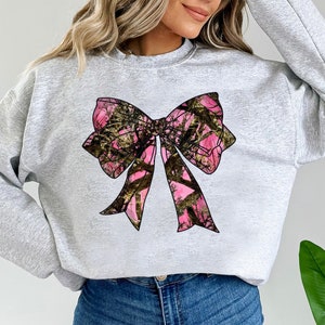 a woman wearing a sweatshirt with a pink bow on it