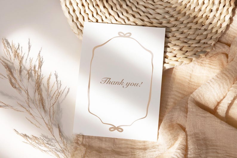 May include: A white card with a gold frame and the text "Thank you!"  The card is sitting on a woven straw mat and a beige fabric.
