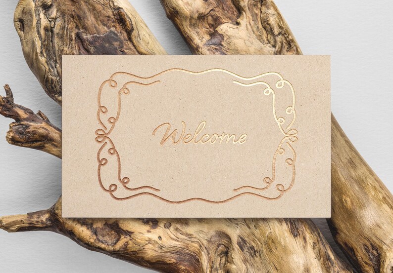 May include: A brown card with a gold foil design of a decorative frame and the word "Welcome" in the center.