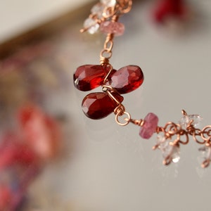 May include: A delicate copper wire bracelet with red garnet and pink and clear quartz gemstones.