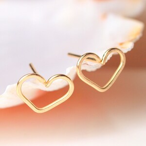 Puede incluir: Un par de pendientes de bot&oacute;n de coraz&oacute;n de oro. Los pendientes son simples y delicados, con un dise&ntilde;o minimalista.