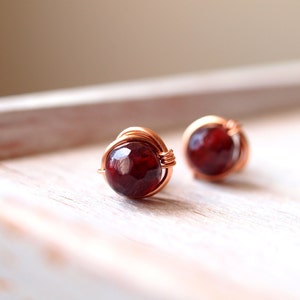Op de afbeelding: Een paar oorringen van koperdraad met rode edelsteen cabochons.