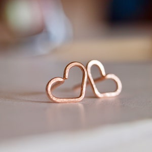 Puede incluir: Un par de pendientes de coraz&oacute;n de oro rosa. Los pendientes son simples y delicados, con un acabado liso.