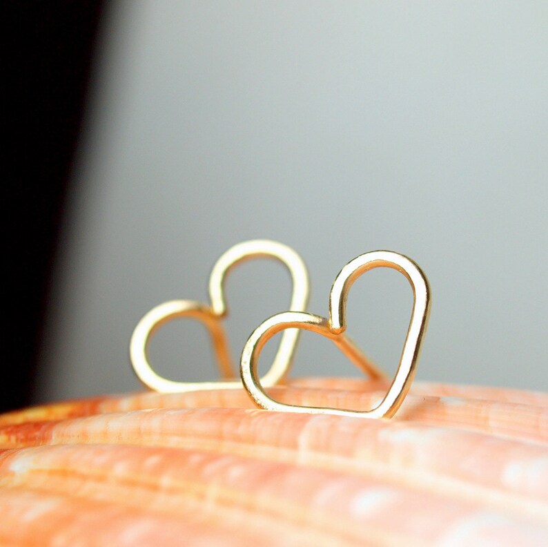 Puede incluir: Un par de pendientes de coraz&oacute;n de oro. Los pendientes son simples y delicados, con un dise&ntilde;o de alambre fino.