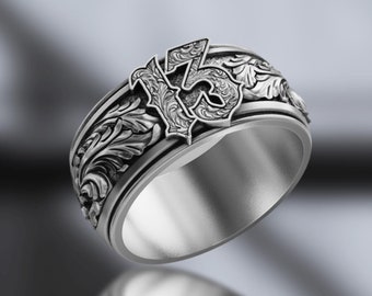 Può includere: Un anello in argento con il numero 13 in rilievo in carattere gotico, circondato da intricati intagli a volute. La fascia presenta un interno lucido e un esterno testurizzato e ossidato. Il logo ASKA è visibile in basso a sinistra.