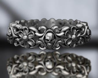 Könnte beinhalten: Ein silberner Ring mit einem Totenkopf- und Blumendesign. Der Ring ist aus Metall gefertigt und hat ein detailliertes Design.
