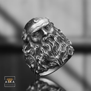 以下が含まれることがあります： ひげを生やした男性の顔の彫刻が施されたシルバーリング。リングはヴィンテージ感があり、顔とひげに複雑なディテールが施されています。歴史的または芸術的なジュエリーを好む方に適した、ステートメントピースのリングです。