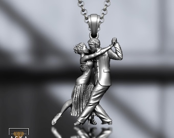 May include: Silver pendant necklace featuring a couple dancing the tango. The pendant depicts a man and woman in formal attire, mid-dance, with intricate details. The chain is a delicate silver link. The pendant is approximately 1.5 inches in height.