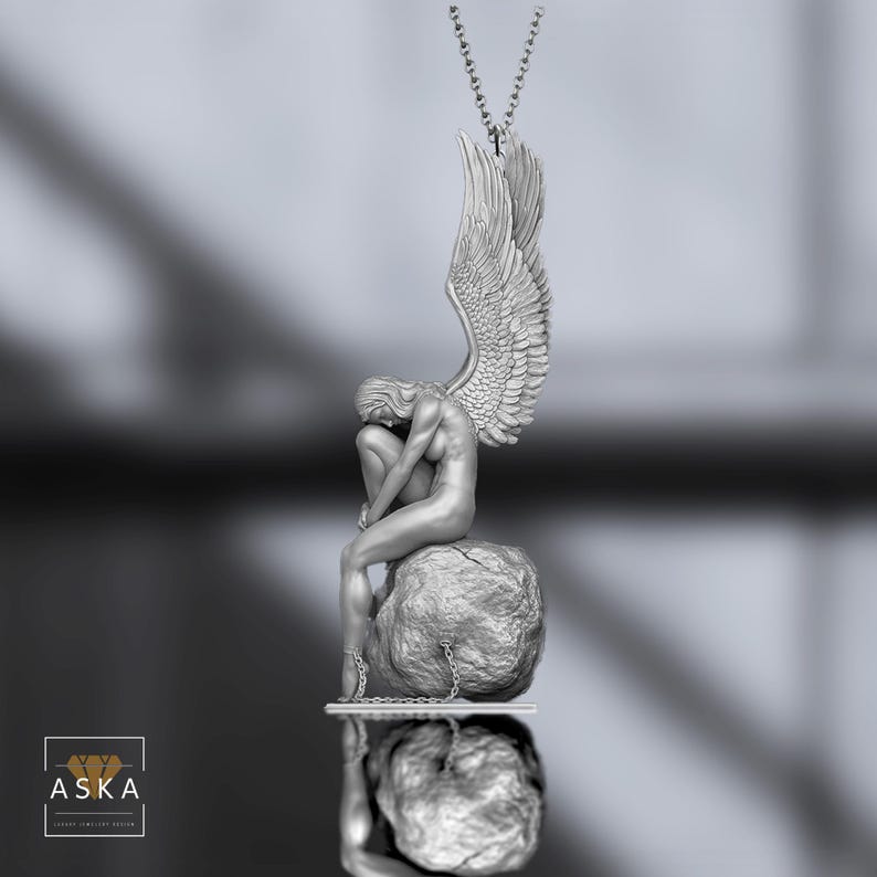Op de afbeelding: Zilverkleurige hangerketting met een gebeeldhouwde figuur van een zittende engel met grote vleugels. De engel zit op een rots, met kettingen om de enkels. De hanger hangt aan een fijne ketting.