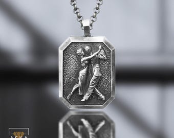 May include: Silver pendant necklace featuring a rectangular pendant with an embossed image of a couple dancing the tango. The pendant is framed with an octagonal border and hangs from a chain.