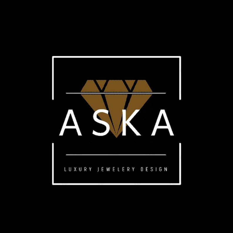Op de afbeelding: Een logo op een zwarte achtergrond met het witte woord "ASKA", met daaronder "LUXURY JEWELRY DESIGN". Een bruine diamantvorm is gecentreerd boven de tekst, binnen een wit rechthoekig kader.