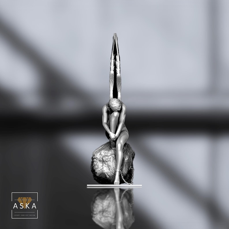 Op de afbeelding: Een grijswaarden sculptuur van een zittende figuur bovenop een rots met textuur, met armen om de knie&euml;n. Boven, een gestileerd vleugelontwerp strekt zich omhoog uit. De sculptuur staat tegen een vage achtergrond, met het woord "ASKA" in de linker benedenhoek.